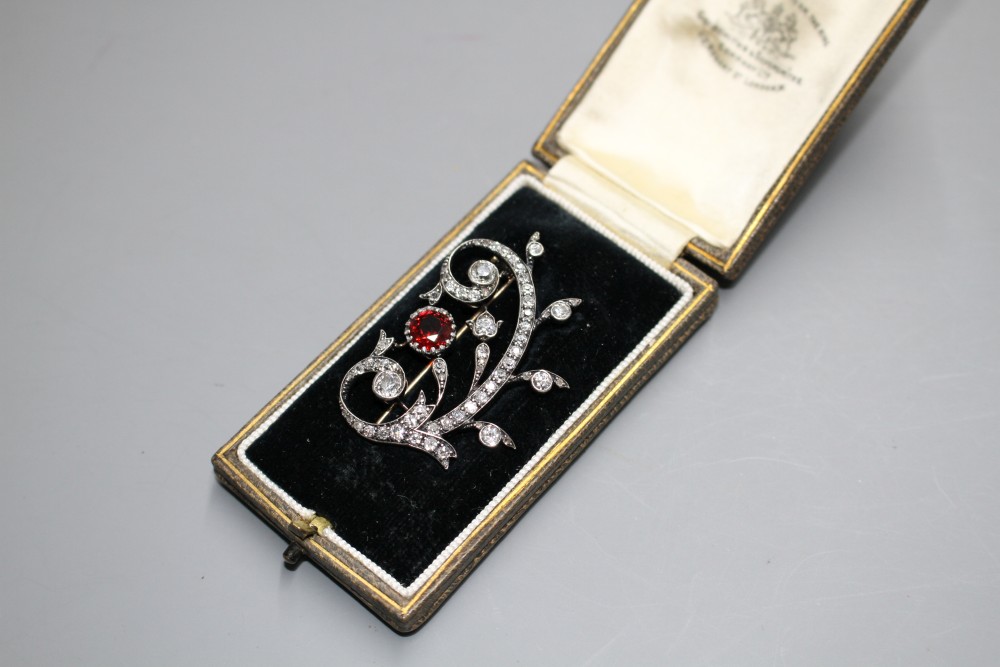 An early 20th century yellow and white metal, red spinel and diamond set foliate scroll brooch,